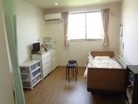 大きな窓が付いた居室は日当たりがよく明るい。ベッドやテレビ、収納家具などが設置されている。