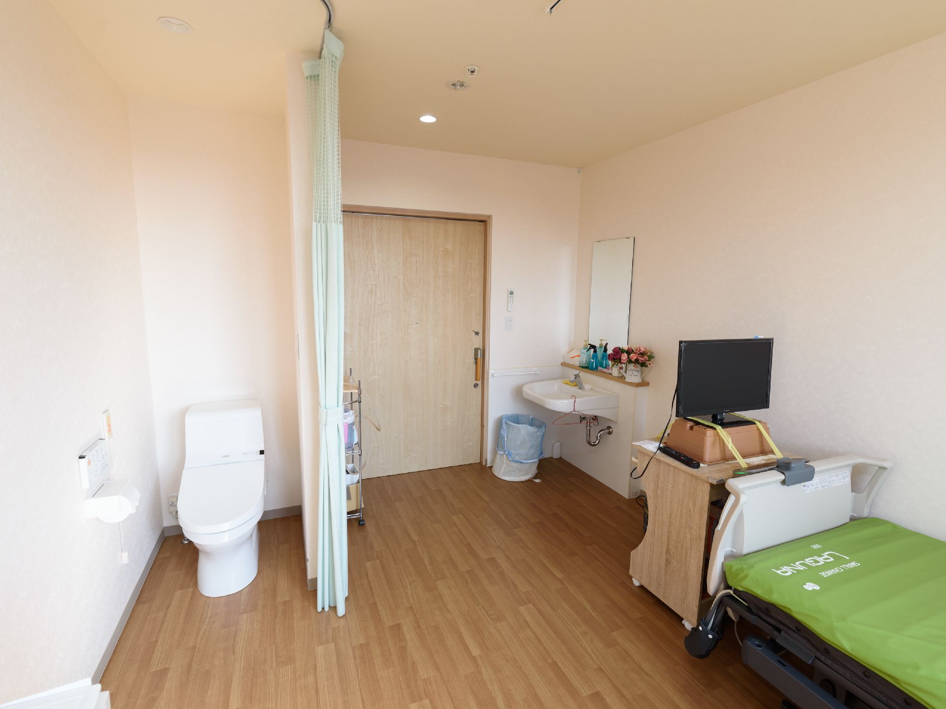 洋式便座が設置された居室で、居住スペースとはカーテンで仕切られている。ドアを入って左側に洗面台がある。