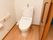 入口が引き戸になっているトイレ。洋式便器が１つ設置されていて、周囲の壁に非常用の呼び出しブザーなどがある。