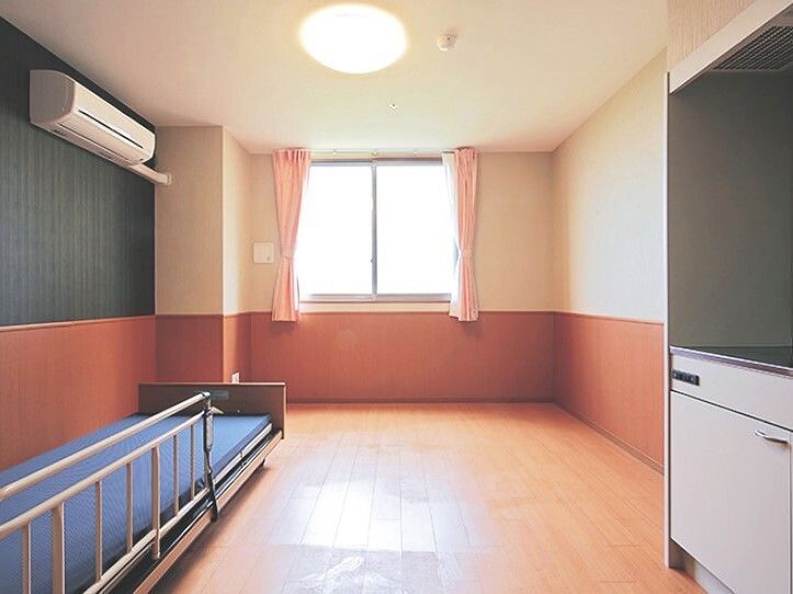 介護ベッドやキッチンが付いたフローリングの部屋には大きな窓があり、壁にはエアコンも付いている。