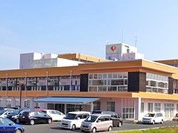 2階建ての建物。駐車場も広く、玄関先には青い屋根もついている。