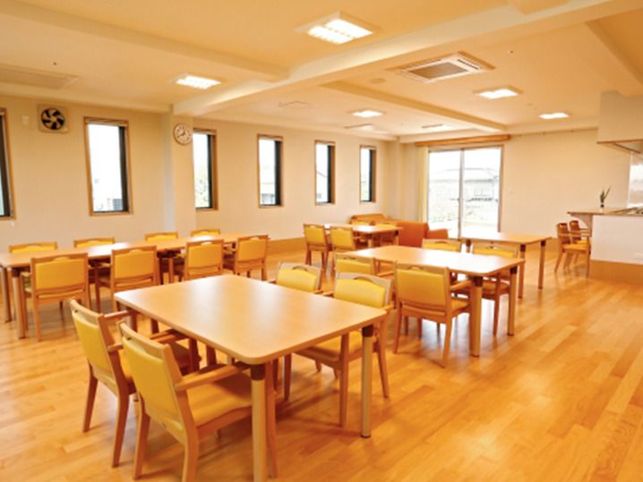 木製のダイニングテーブルが複数置かれた食堂には大小の窓があり、奥にはキッチンも設置されている。
