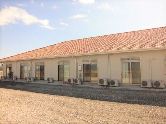 広い敷地に建っている平屋建ての建物。オレンジ色の屋根が付き、温かい雰囲気。