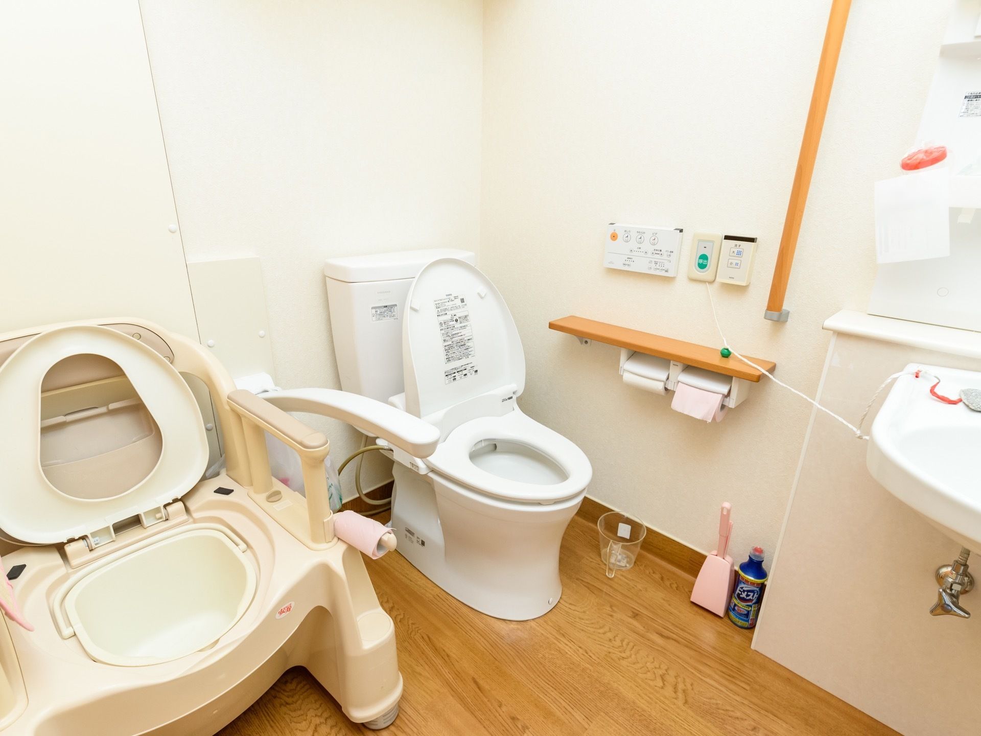 共同トイレには、通常の便器の他に、幅の広い汚物処理用の便器も設置されている。緊急呼び出しボタンのひもが洗面台の方につながっている。