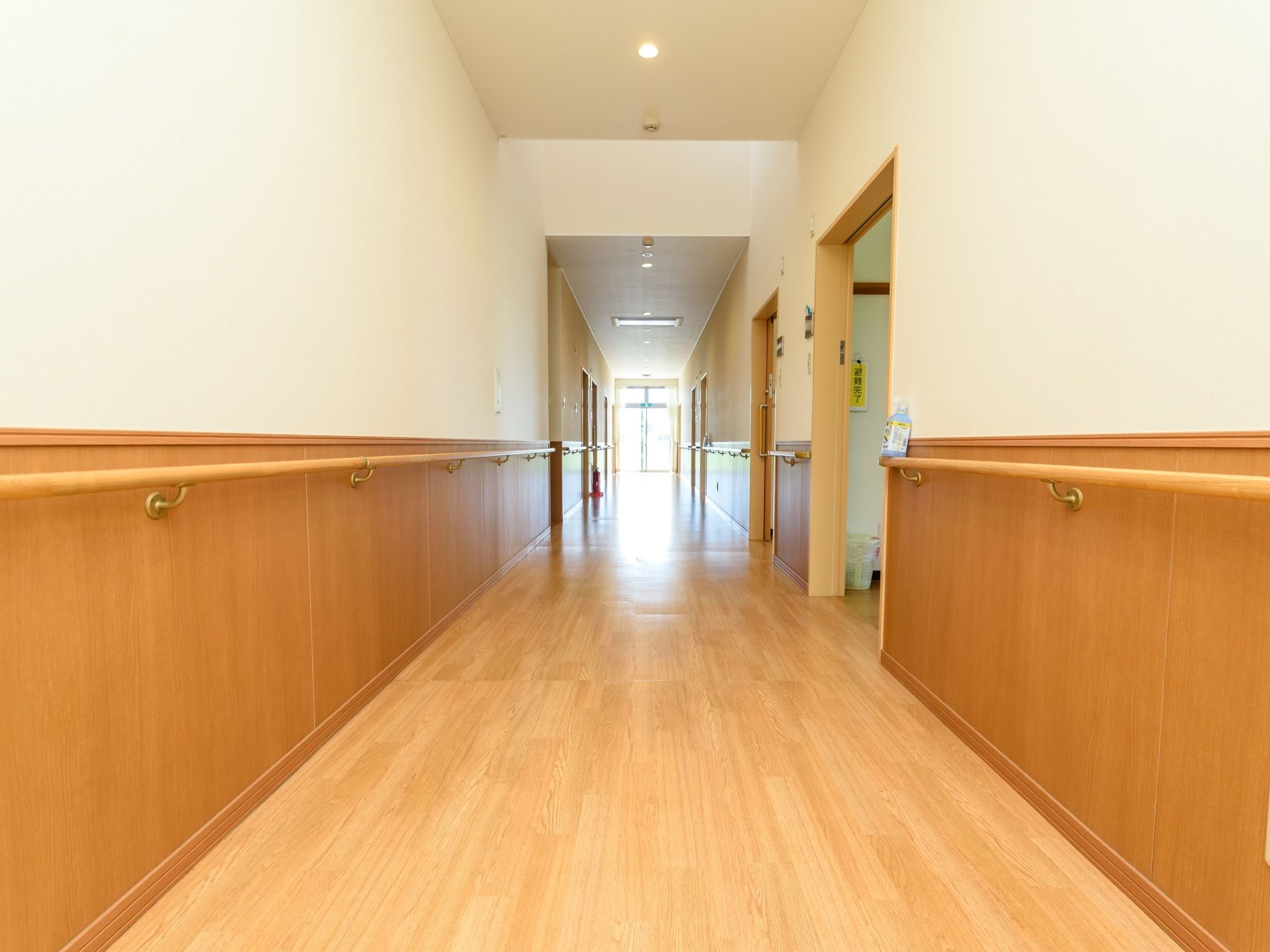 廊下は、つきあたりの掃き出し窓からの採光で明るくなっている。居室などの入口以外の壁には切れ目なく手すりが設置されている。