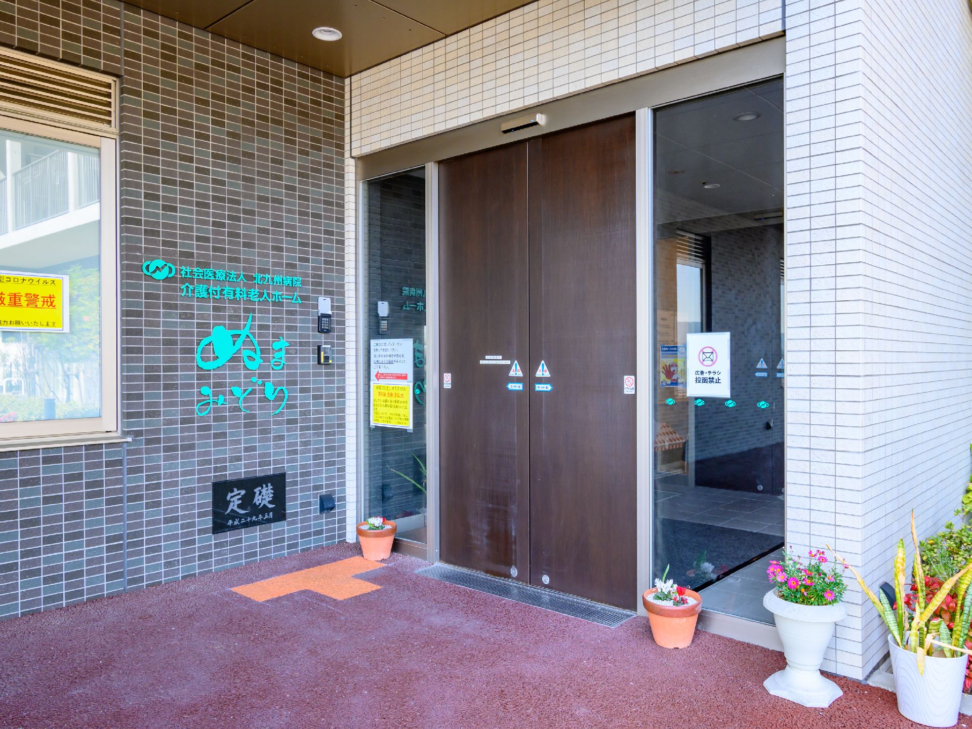 服薬をうながすスタッフとそれに従って薬を飲もうとしている女性。施設内の一場面