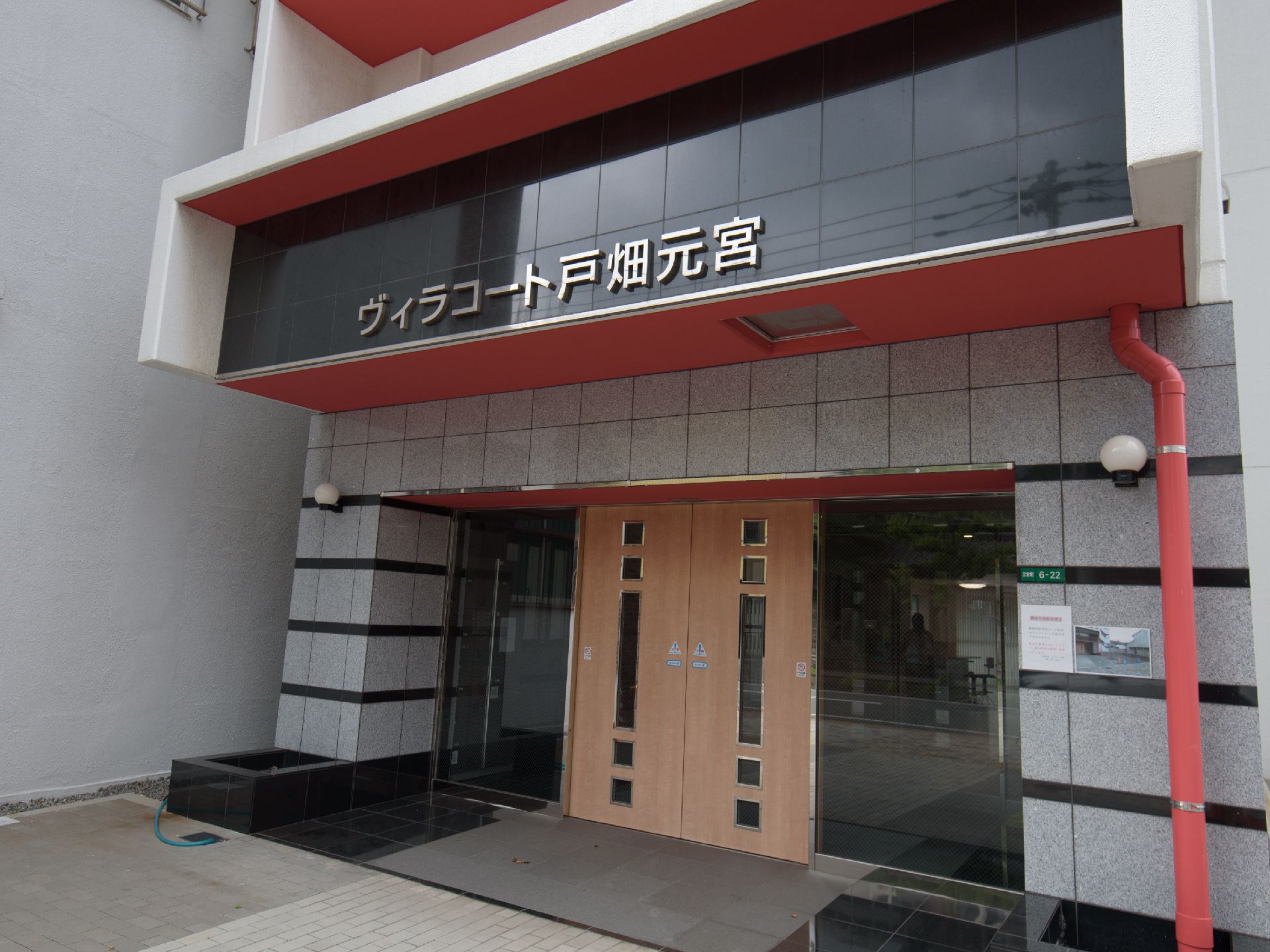 石組みのアーチに黒いガラスと木の自動ドアがおしゃれな入口の外観