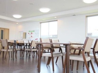 椅子とテーブルがたくさん並んでいるサービス付き高齢者向け住宅のリビングスペース