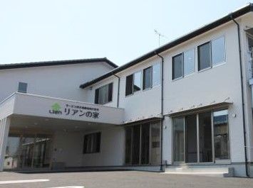 ２階建ての住宅のような雰囲気の施設外観。手前に駐車場スペースがある様子