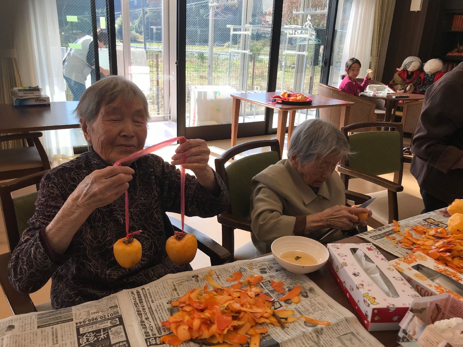 施設のレクリエーションで干し柿を作っている様子。柿を剥いている高齢者の写真