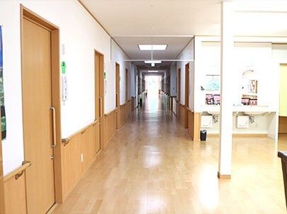 居室のドアはスライド式で、壁には手すりが付きまっすぐな廊下が続いている。右側には共有スペースもある。