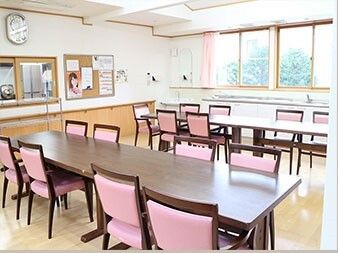 厨房がすぐそばにある食堂にはピンクの椅子がセットされたダイニングテーブルセットが置かれ、大きな窓がある。