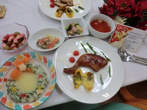 白いテーブルクロスの上に並べられた料理と赤い花とメッセージカード