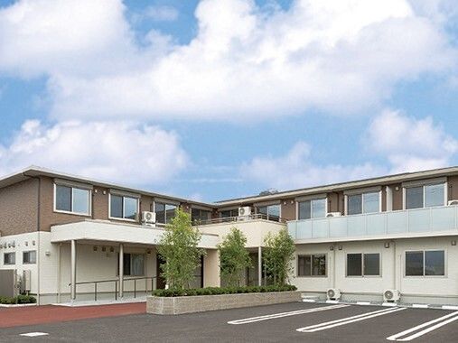 エル字型の2階建ての建物。玄関先には手すり付きのスロープや屋根が付いている。
