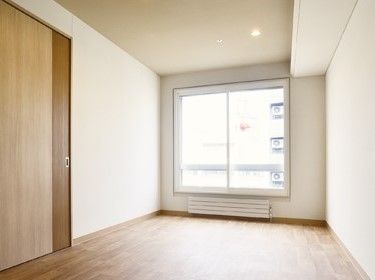 窓の下には暖房器具があり、大型の収納スペースがあるフローリングの居室。