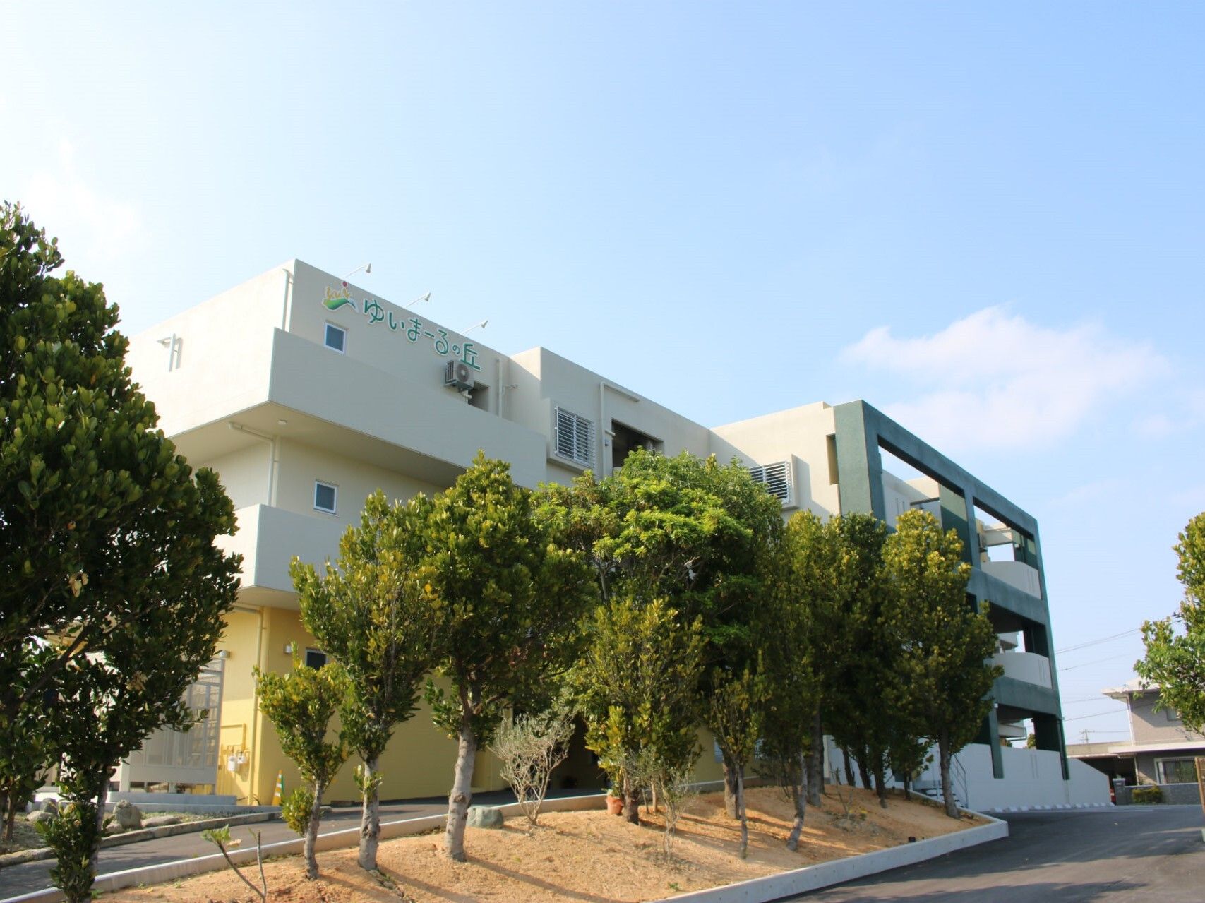 白を基調とした3階建ての建物は重厚感があり、建物の周りには草木も植えられている。