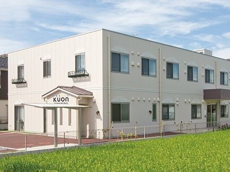 ２階建ての建物の周りには段差がなく駐車スペースもあり、周辺にも緑が多い。