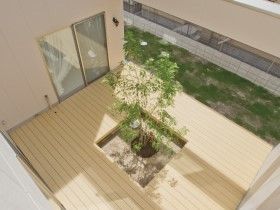 ウッドデッキが敷かれた中庭には中央に大きな木が植えられている。