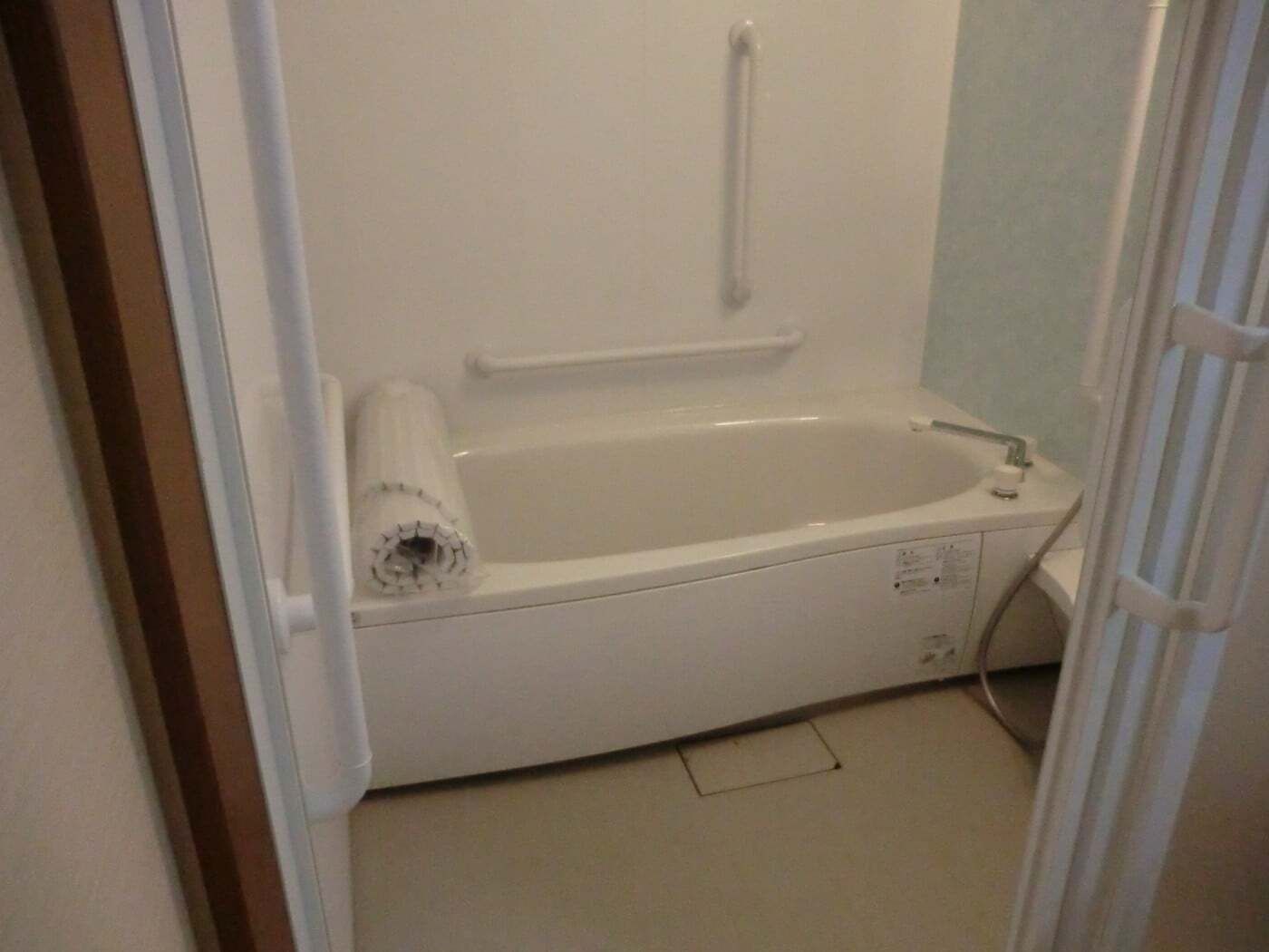 縦横に複数手すりが付いた浴室には一人用の浴槽が設置され、浴槽用のふたも浴槽の上に置かれている。
