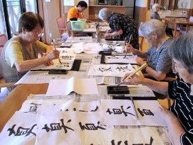書道をしている施設入居者の写真。真剣な表情で取り組んでいる様子