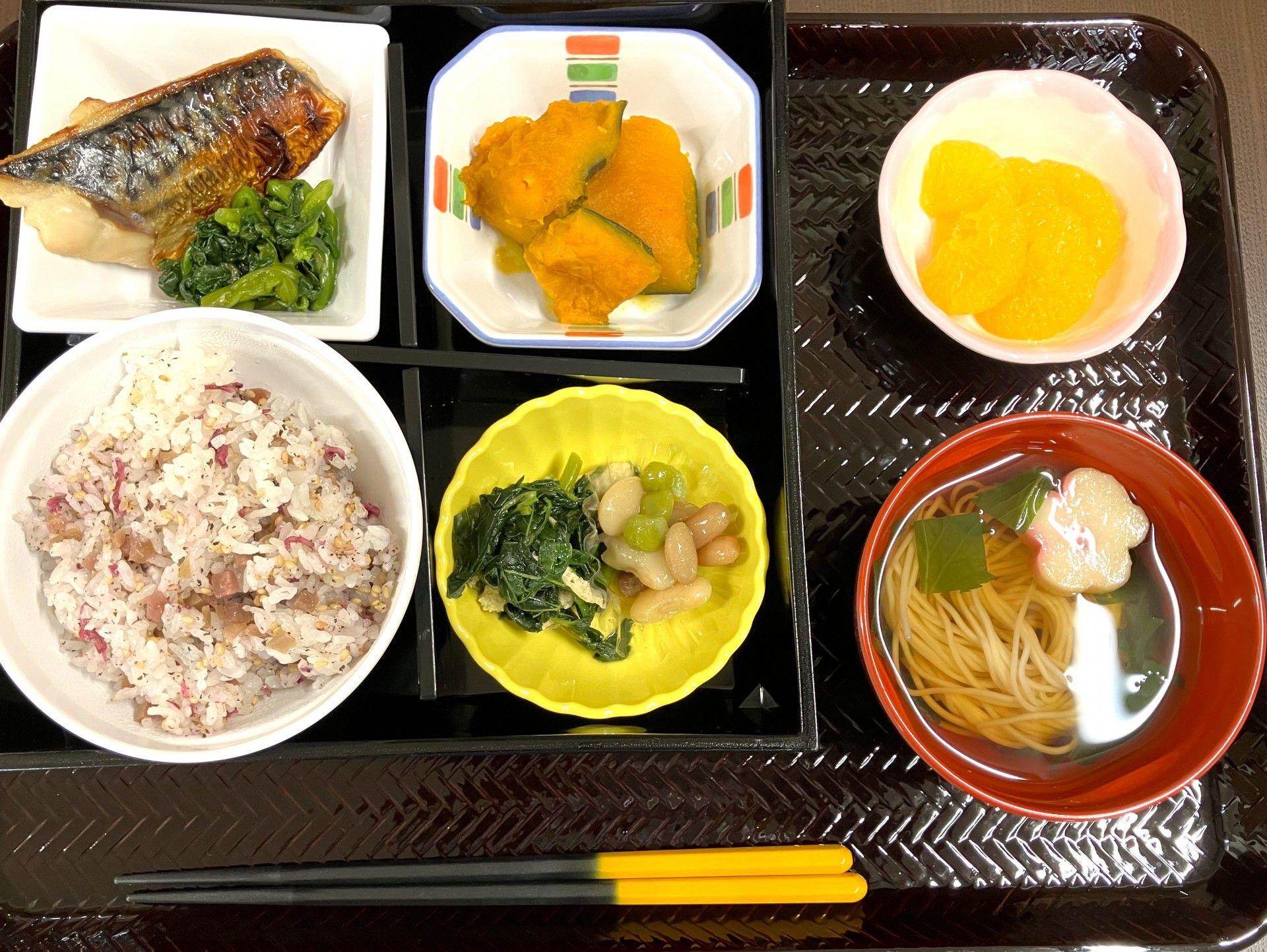 キウイフルーツや白いご飯、みそ汁、あんかけ豆腐、野菜の和え物、焼き鮭などが並んでいる。