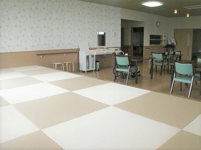 奥の方にテーブルと椅子、手前に畳のこあがりがある施設内のリラックススペース