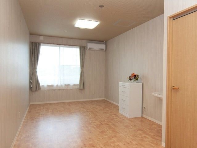 広めのワンルームタイプの部屋。エアコンと小さなタンスがある部屋の様子