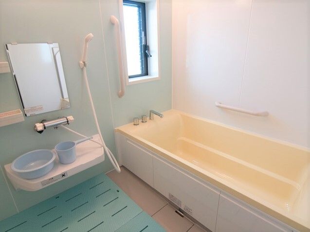 壁に手すりが取り付けられている施設内の浴室の様子。大きめの浴槽がある浴室