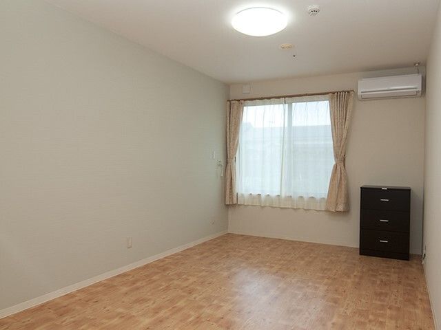 エアコンと小さなタンスが置かれているワンルームの様子。施設内の居室