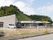 緑あふれる山々に囲まれた平屋建てのホーム。駐車スペースには2台の車も止まっている。