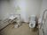 広い個室のトイレに洗面台と便器が並んで置かれている。洗面台の両側には手すりが設置されている。便器の横にも可動式のひじ掛けと手すりがある。
