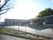 １階建ての四角い建物がある。緩やかな坂が続いており、敷地内は低いフェンスで覆われている。周囲には山が見え、背後には木々が繁っている。