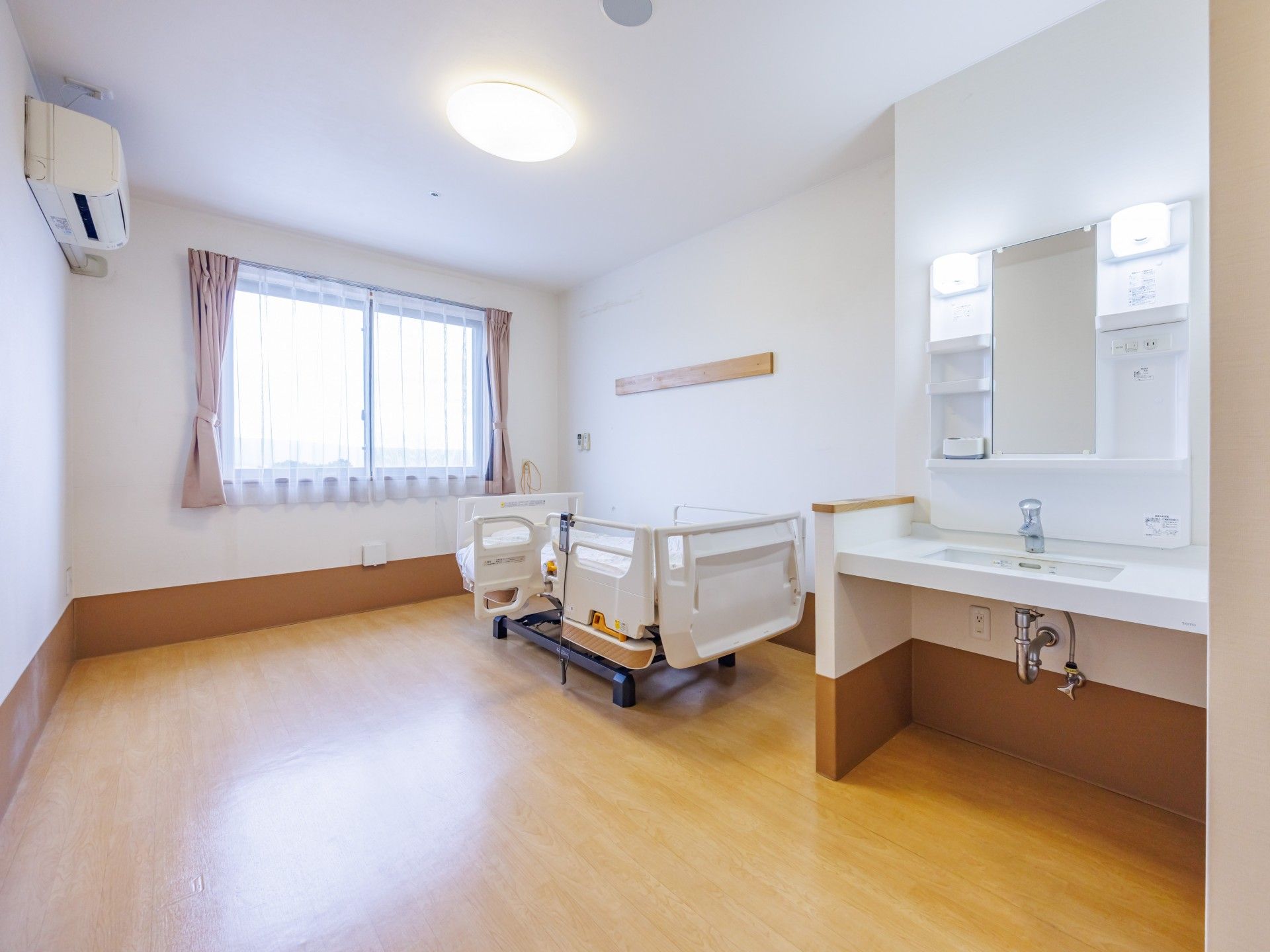 明るい個室のベッドと洗面台