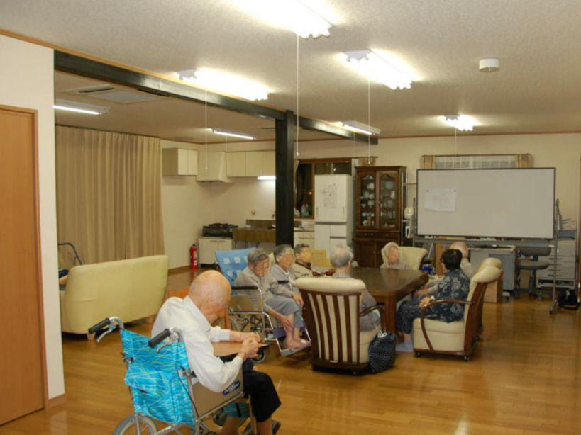 大きなテーブルを囲んで談笑している高齢者たち。車いすを利用している人も一緒にテーブルを囲んでいる。