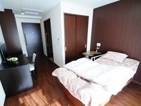 なにかを指さして笑顔で話している車いすの女性とそれを押している介護スタッフの様子