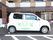 白い４ドアの施設専用車が駐車場に停められている。側面に緑と黄緑のデザイン文字で、大きく横書きに施設名を表示している。