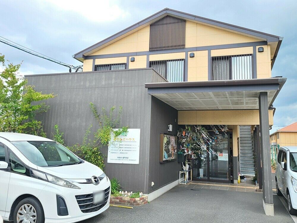 笑顔でこちらを向いている施設のスタッフと車いすに乗っている高齢者の様子。施設で写された写真