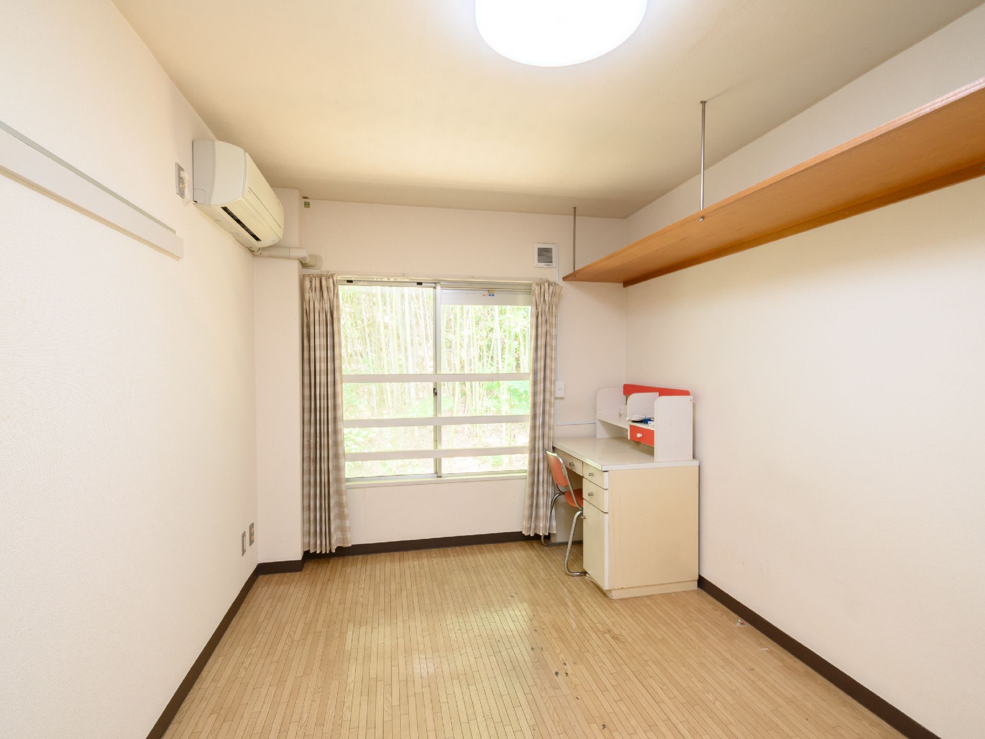 隅に白い机と木製の椅子のみが置かれた白い壁の部屋