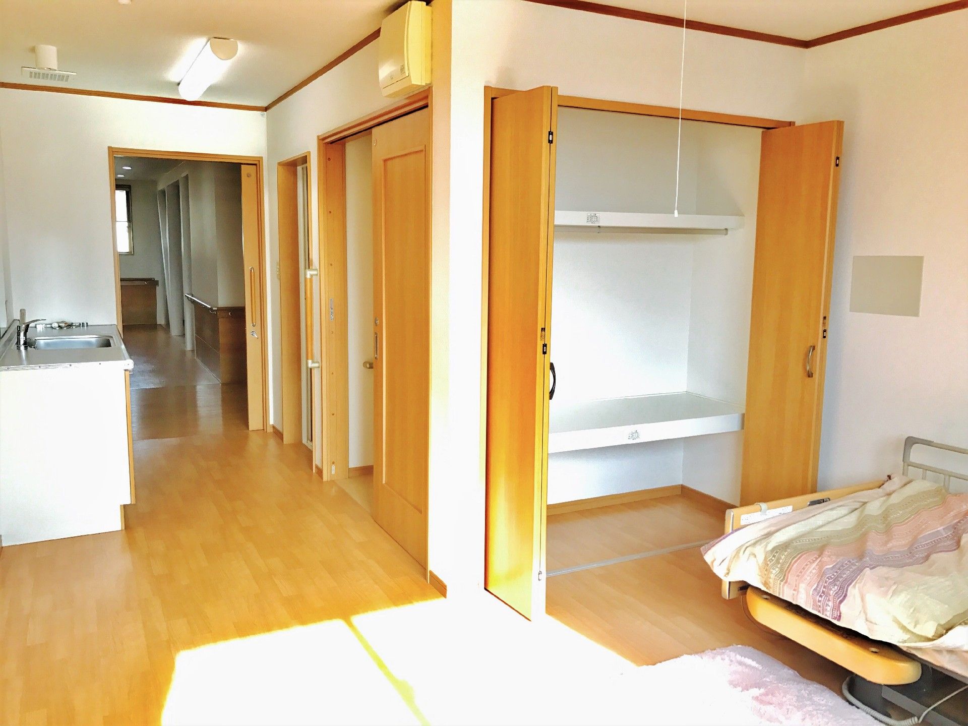 トイレや収納が付いた広々としたフローリングの居室には寝具付きの介護用ベッドがある。