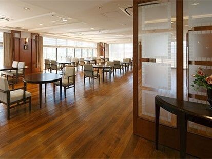 ２～４人掛けのテーブルセットが並んだフローリングの食堂。温かい雰囲気で窓も大きい。