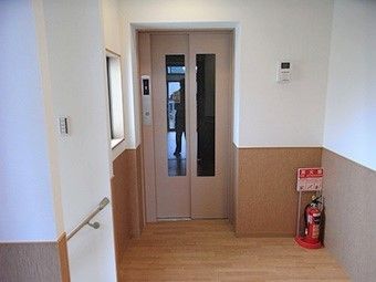 エレベーターのそばには消火器が置かれ、壁には手すりが設置されている。