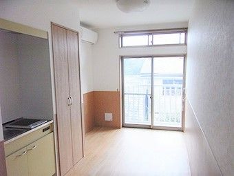 フローリングの居室。キッチンやエアコン、収納があるシンプルな部屋。