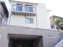 3階建ての建物。2階と3階にはベランダがあり、1階には駐車スペースがある。
