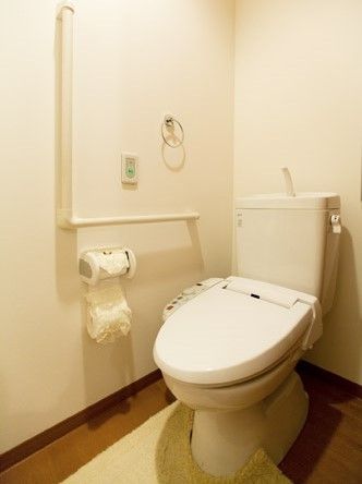 呼び出しボタンや手すりが付いたトイレ。シンプルな温水便座。