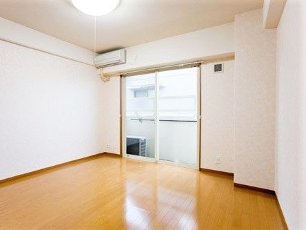 エアコンが付いたシンプルな居室。大きな窓の外にはベランダもついている。