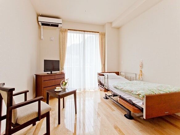右側にベッド、左側に椅子が置いてある小さなワンルームタイプの部屋の様子