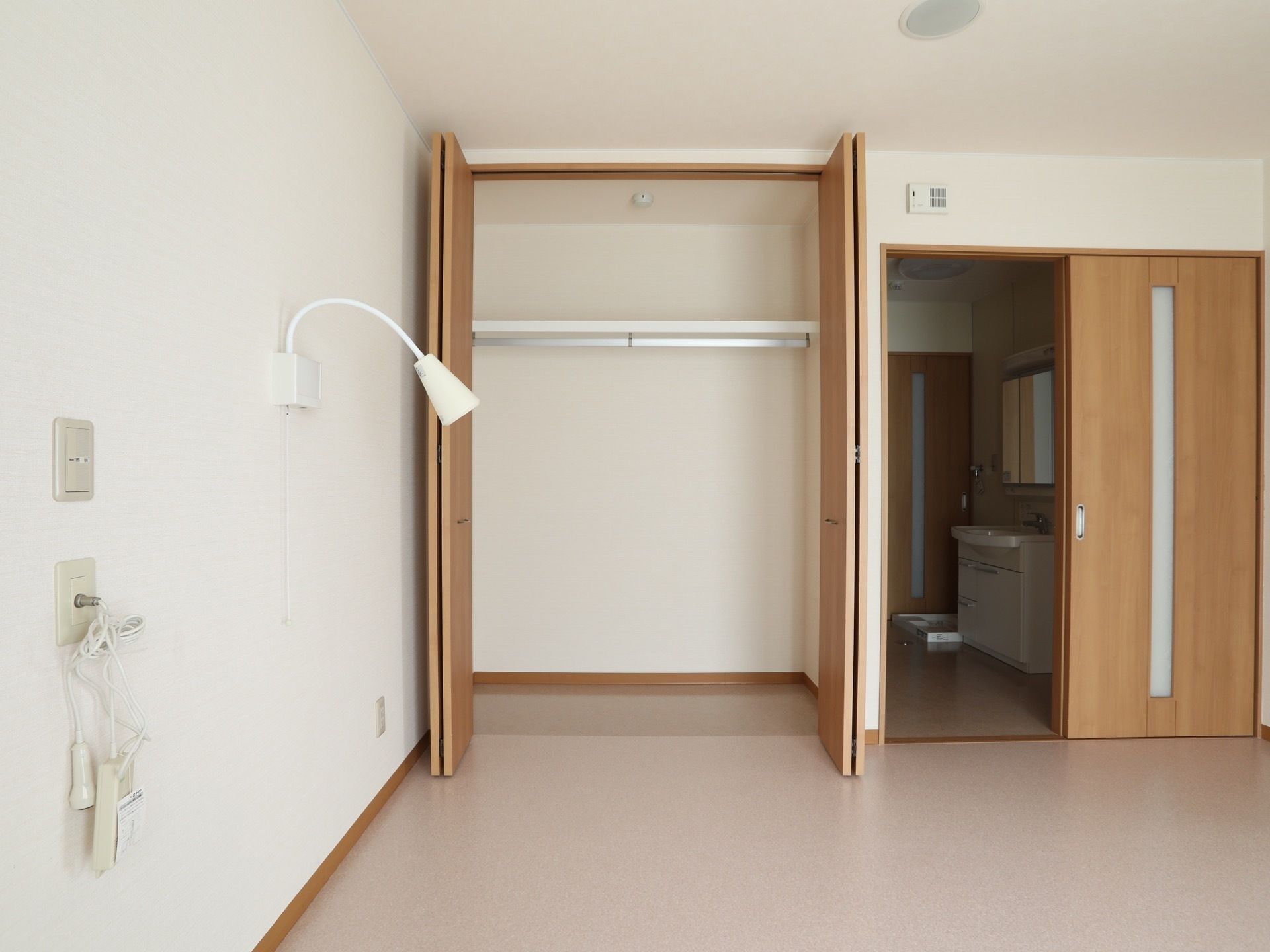 居室の角に観音開きのクローゼットが設けられている。引き戸の奥には洗面台と洗濯機置き場が設けられている。