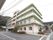 自然豊かな土地に４階建ての施設が建っている。敷地はアスファルト舗装されており、駐車スペースになっている。