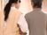 ピンクのエプロンを付けた女性スタッフと白髪の高齢女性が腕を組んで歩いている様子。