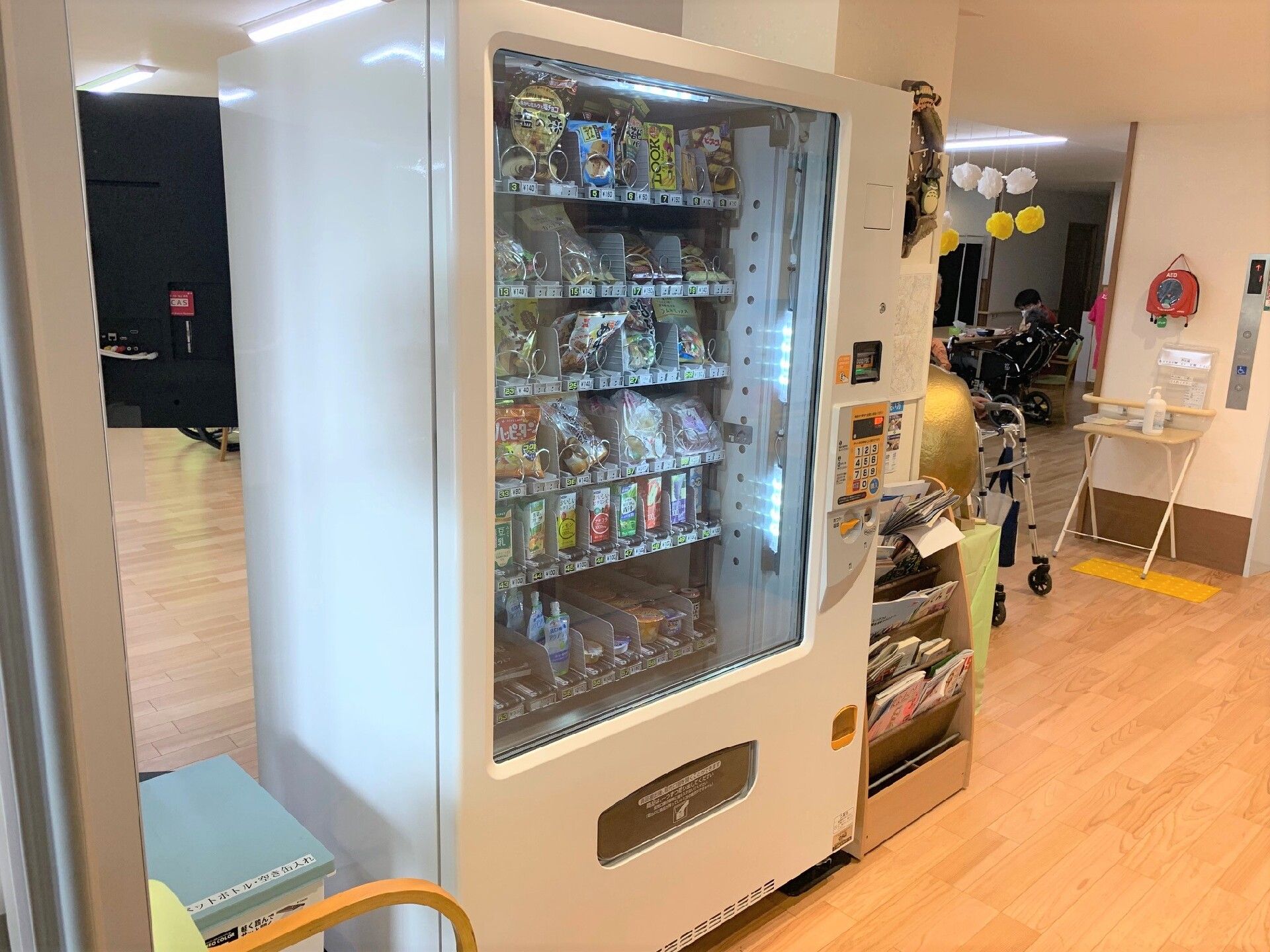 大きな自動販売機ではいろいろな種類のスナックを販売中。すぐ横には雑誌が入ったラックがある。